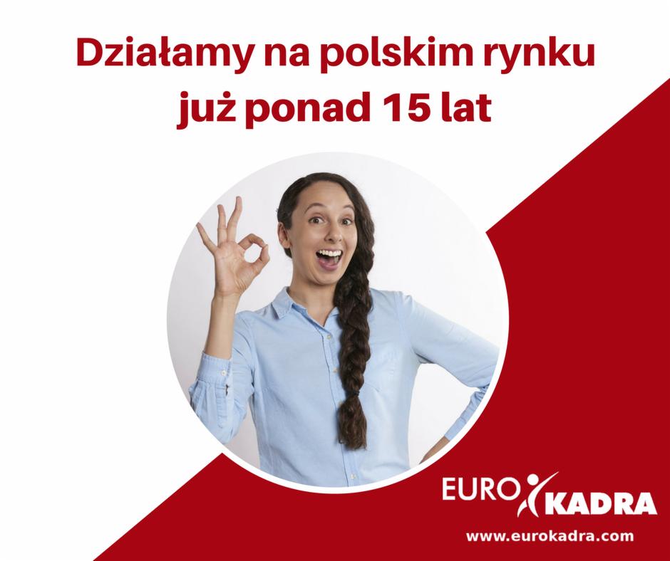 Uśmiechnięta kobieta z warkoczem, ubrana w niebieską koszulę, pokazuje znak 'OK' na tle grafiki z napisem 'Działamy na polskim rynku już ponad 15 lat' i logo firmy Eurokadra.