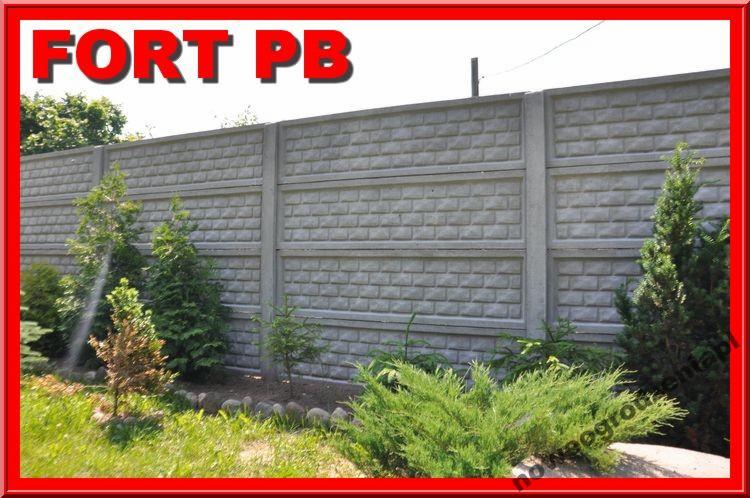 Szary, betonowy płot modułowy z teksturą cegły, otoczony zielenią trawnika i krzewów. Widoczny fragment ogrodu z roślinami.