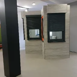 Wystawka okien z roletami zewnętrznymi w salonie w Wadowicach, prezentująca różne konfiguracje i kolory ram okiennych.