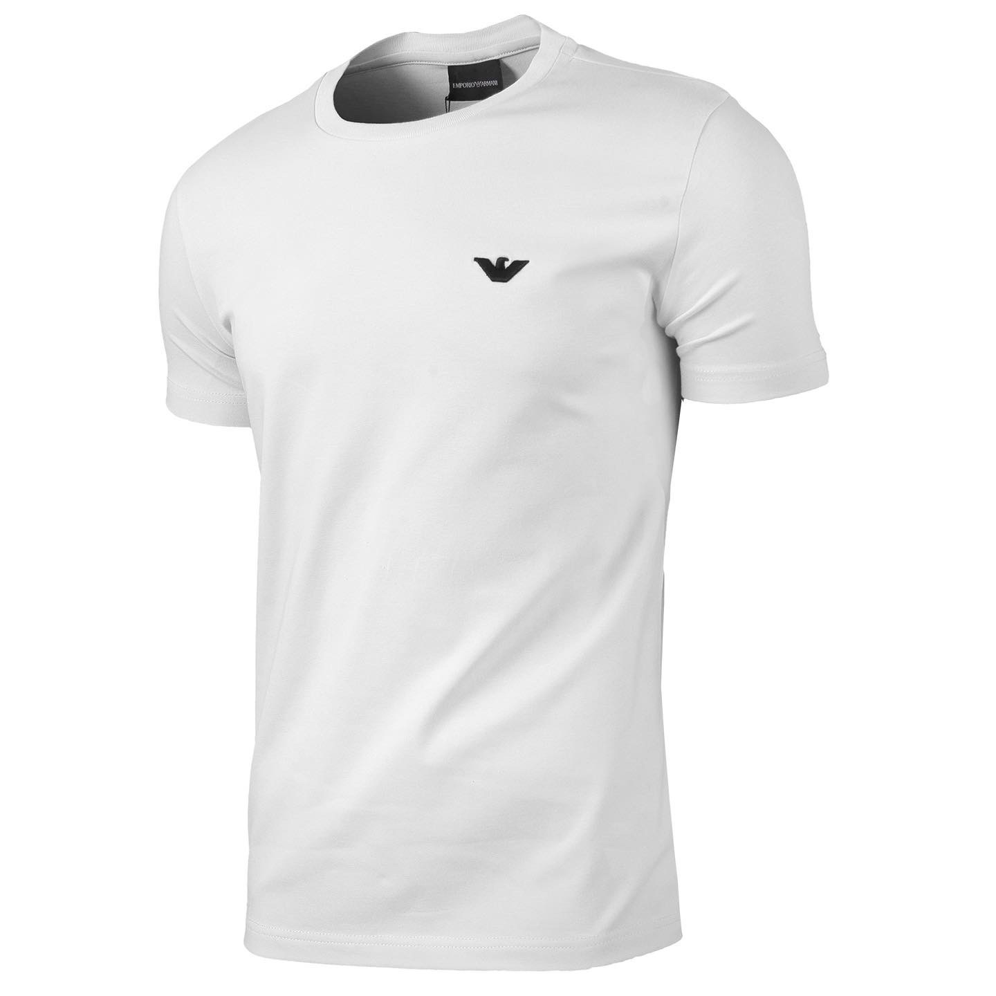 Precyzyjne ujęcie białego T-shirtu z krótkim rękawem i małym, czarnym logo na piersi, widoczne delikatne cieniowanie materiału.