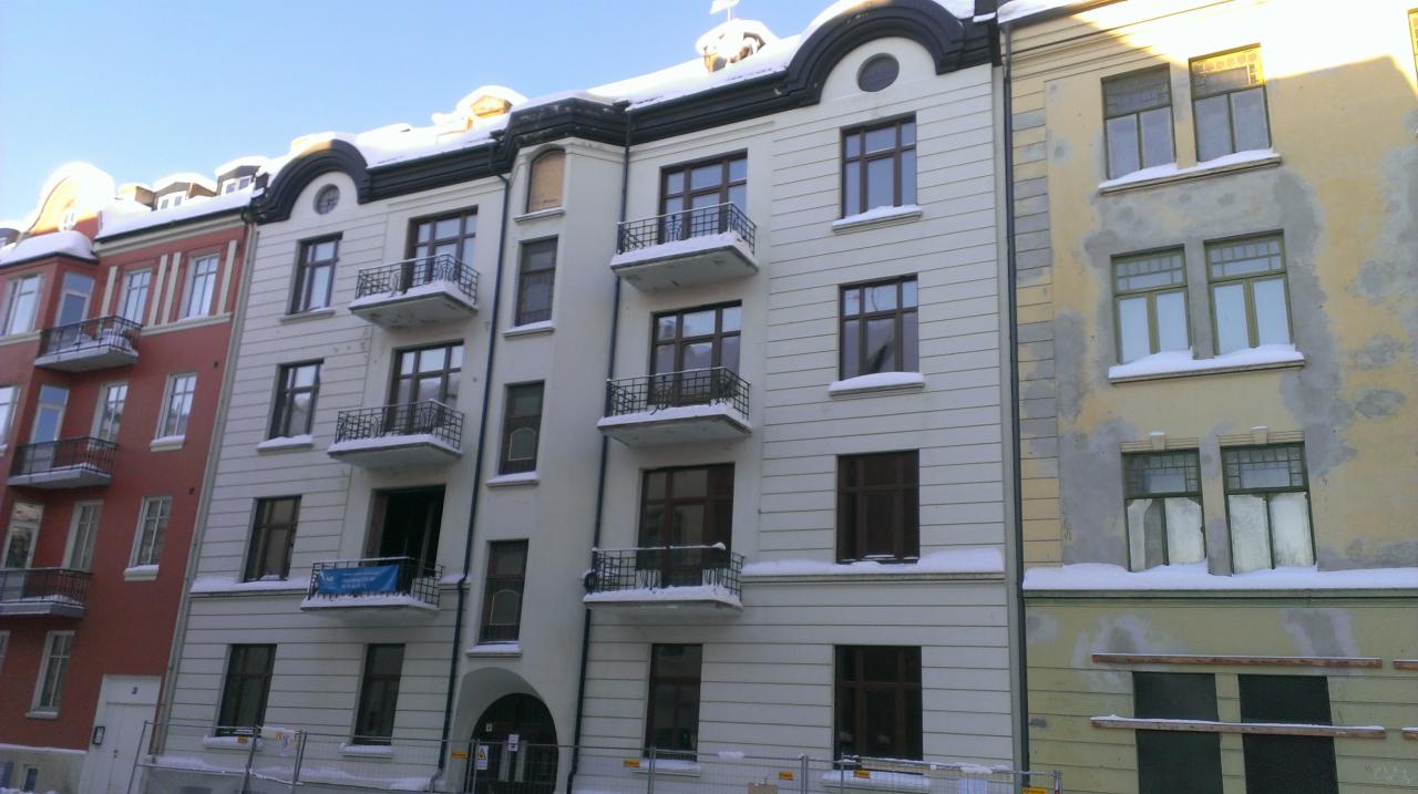 Fasada kamienicy w Trondheim z oknami i balkonami, częściowo pokryta śniegiem.