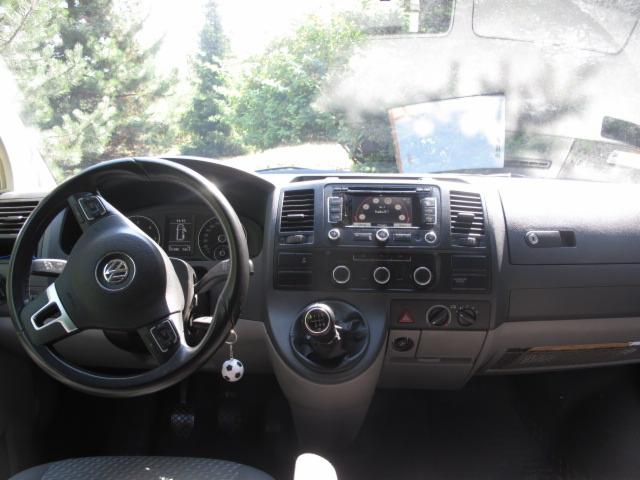 Wnętrze Volkswagena Transportera z kierownicą po lewej stronie, deską rozdzielczą i kluczykami z breloczkiem piłki nożnej. Widok z perspektywy pasażera.