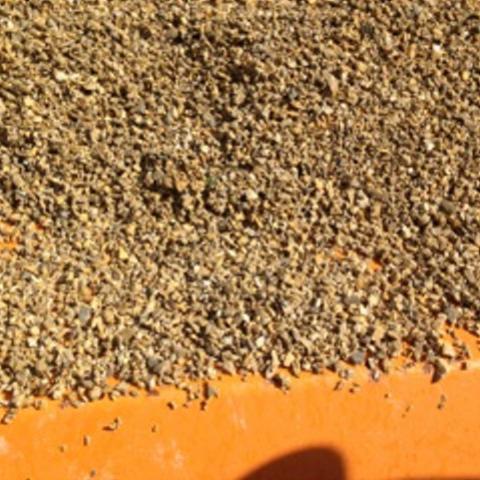 Bliski plan brązowych kruszyw dolomitowych na pomarańczowym podłożu, oświetlonych naturalnym światłem.