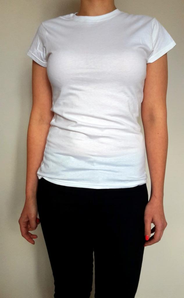 Osoba w białej koszulce z krótkim rękawem i czarnych legginsach na jasnym tle. Widoczny tors i fragment rąk. Czerwony lakier na paznokciach.