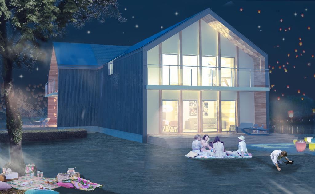 Nowoczesny dom szkieletowy z dużymi przeszkleniami, oświetlony nocą, z grupą osób na pikniku przed budynkiem. W tle lampiony.