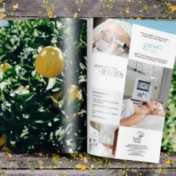 Otwarta broszura leżąca na drewnianym stole. Po lewej stronie widok cytryny na drzewie, po prawej stronie informacje o salonie kosmetycznym Geneo Perle i zabiegach kosmetycznych.