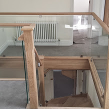 Szklana balustrada z drewnianymi elementami w Jastrzębiu-Zdroju. Widok z góry na schody z jasnego drewna i przeszklone barierki. Nowoczesny design.