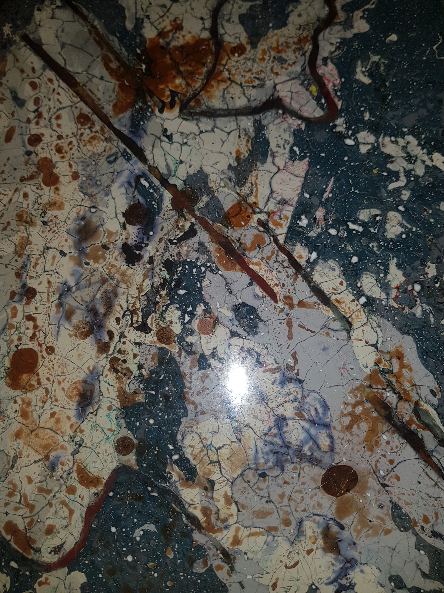 Powierzchnia z efektem marmoryzacji w odcieniach bieli, szarości, brązu i granatu, z widocznymi spękaniami i żyłkami imitującymi naturalny kamień.