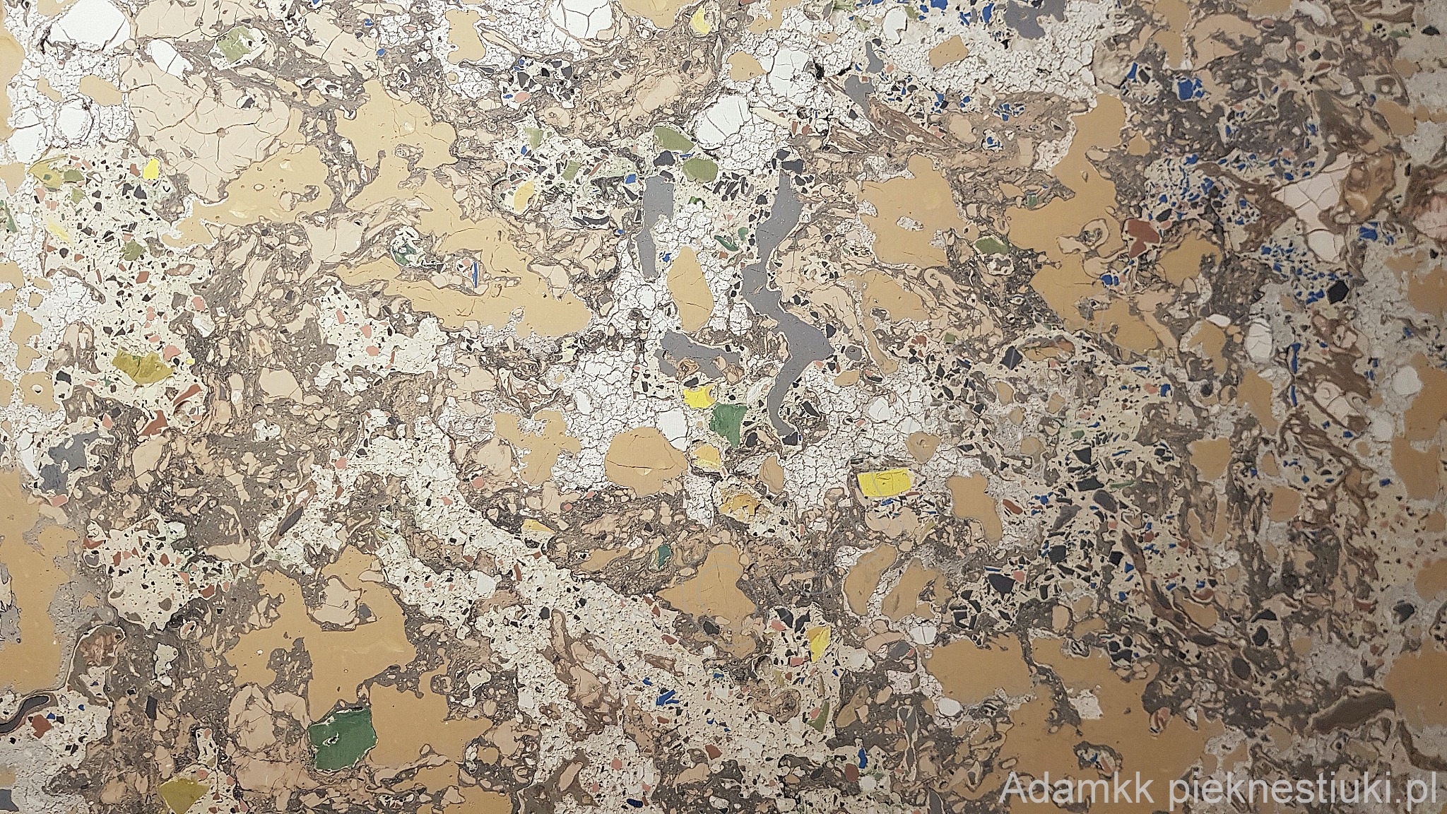 Zbliżenie na powierzchnię imitującą marmur z widocznymi żyłkami i kolorowymi fragmentami, przypominająca stiuk w odcieniach beżu, brązu i bieli.