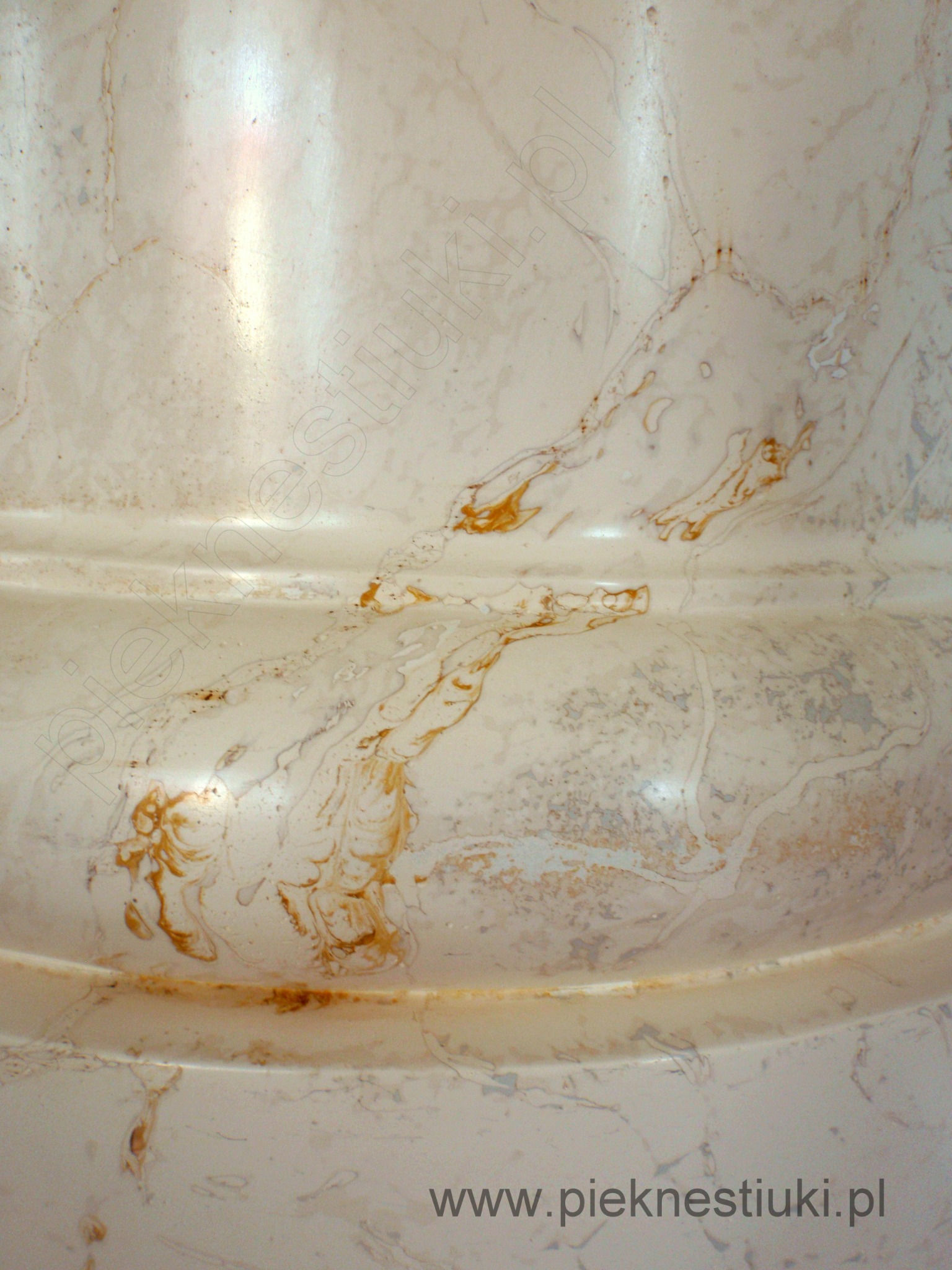 Fragment stiuku imitującego marmur z widocznymi żyłkami i przetarciami, wykonanego w odcieniach beżu i brązu, z delikatnym połyskiem.