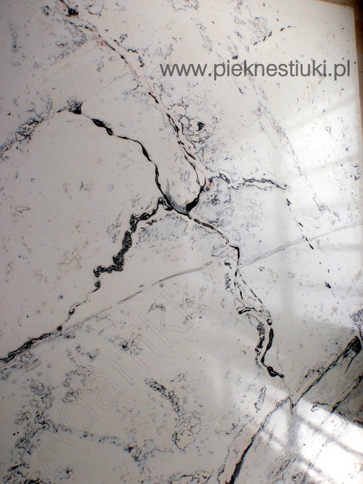 Biała powierzchnia z czarnymi żyłkami imitująca marmur, wykonana techniką stiuku porcelanowego.