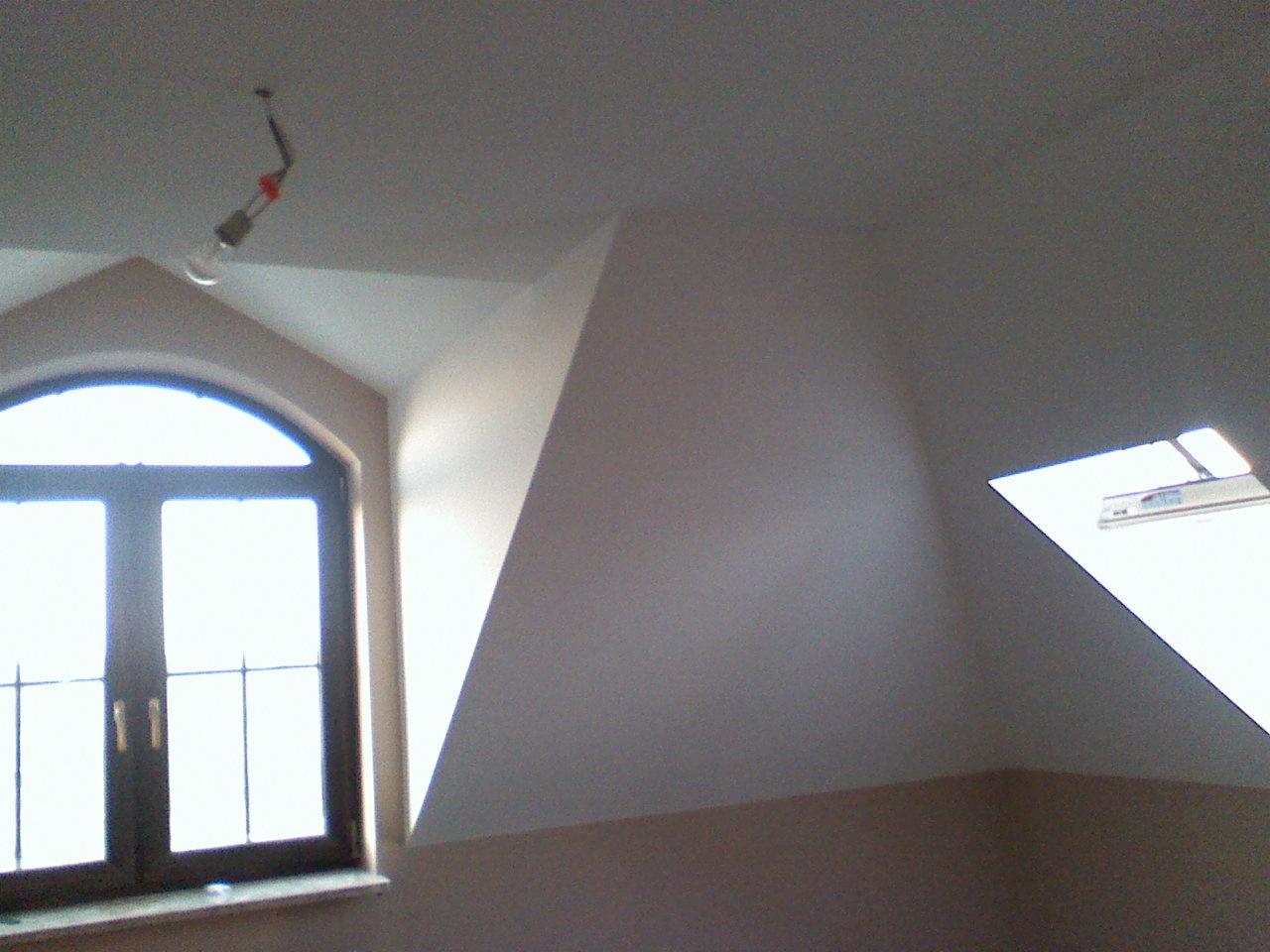 Gładź na poddaszu w Łukowie: Świeżo pomalowane ściany i sufit na poddaszu z oknami dachowymi i pionowymi. Widoczne gniazdko elektryczne na kablu.