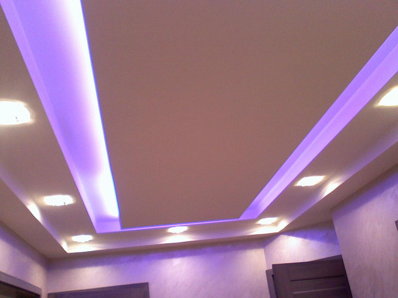 Podwieszany sufit z oświetleniem LED w kolorze fioletowym, zamontowany w jasnym pomieszczeniu. Widoczne drzwi w tle.