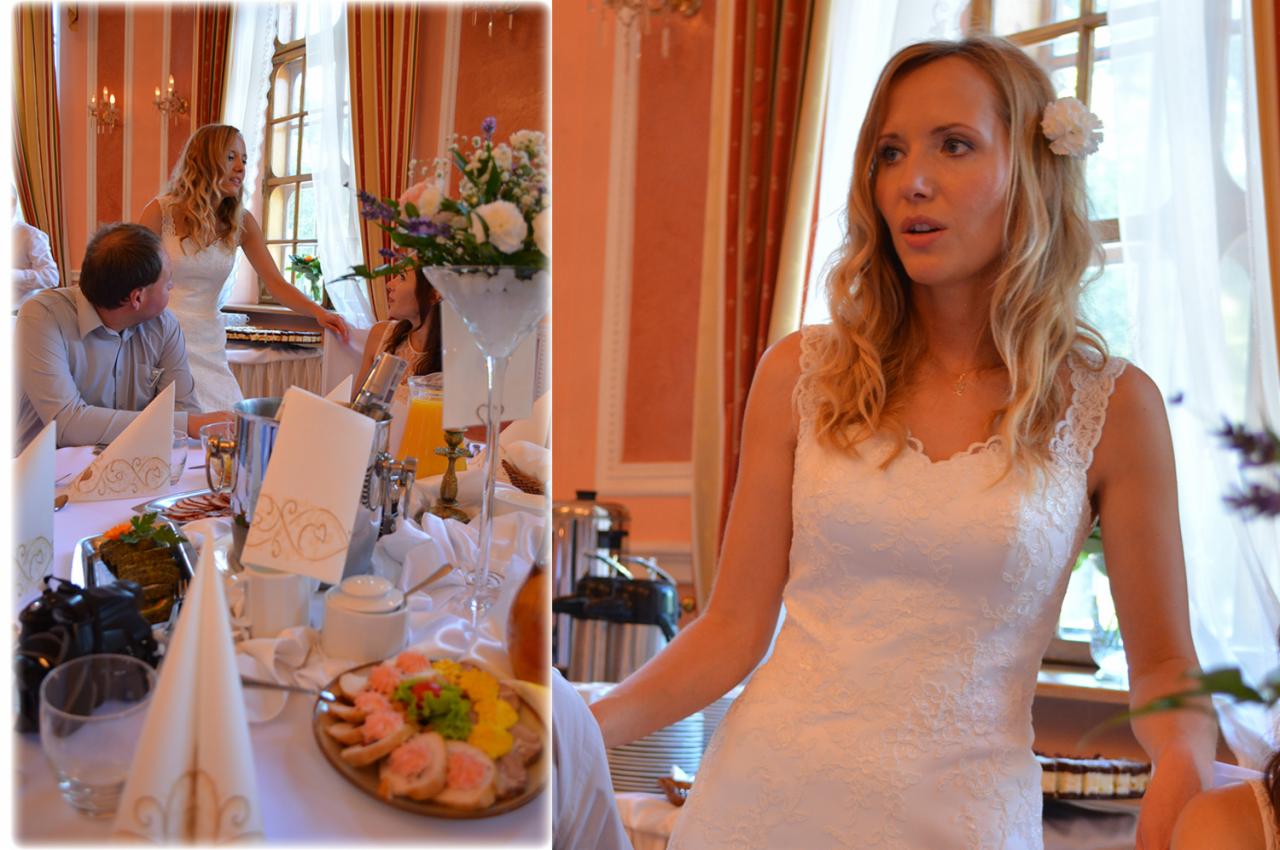 Panna młoda w białej sukni z kwiatem we włosach, przemawiająca podczas przyjęcia weselnego; w tle nakryty stół z przekąskami, napojami i dekoracjami.