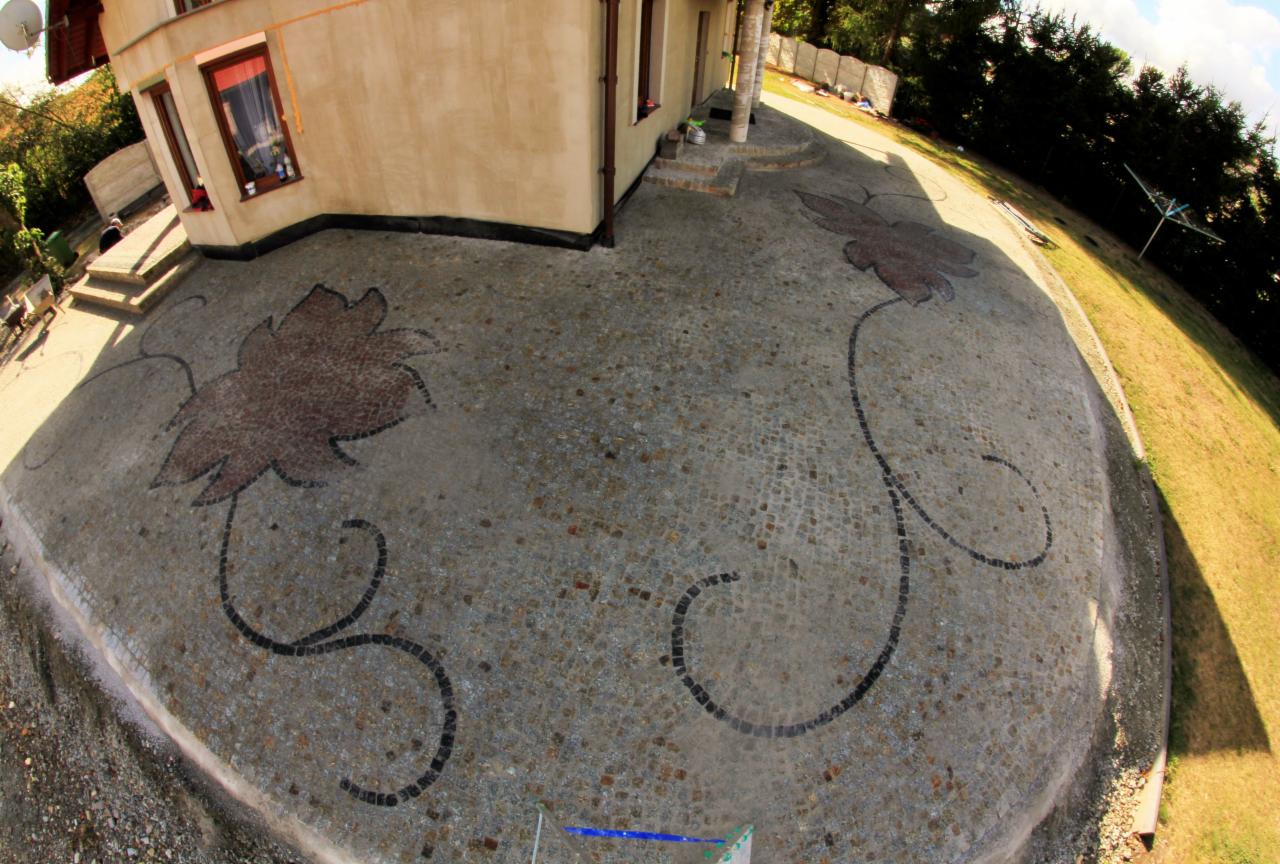 Ogród z kostki granitowej z motywem liści winogron ułożonym w mozaikę. Widok z góry, dom w tle. Artystyczne wykończenie nawierzchni.