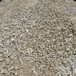 G&oacute;ra kruszywa o frakcji 0-63 mm, widok z bliska, jasne kamienie na tle ziemi.