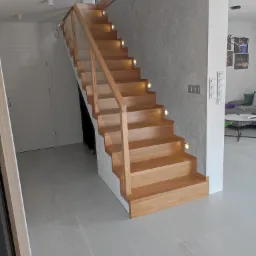 Nowoczesne schody z drewna i szkła z podświetleniem LED w domu we Wrocławiu, widok z dołu.