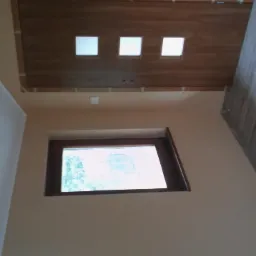 Wykończone wnętrze: drewniany sufit z oknami świetlnymi, okno w ścianie i panele podłogowe. Nietypowy kadr z dołu, perspektywa z rogu pokoju.