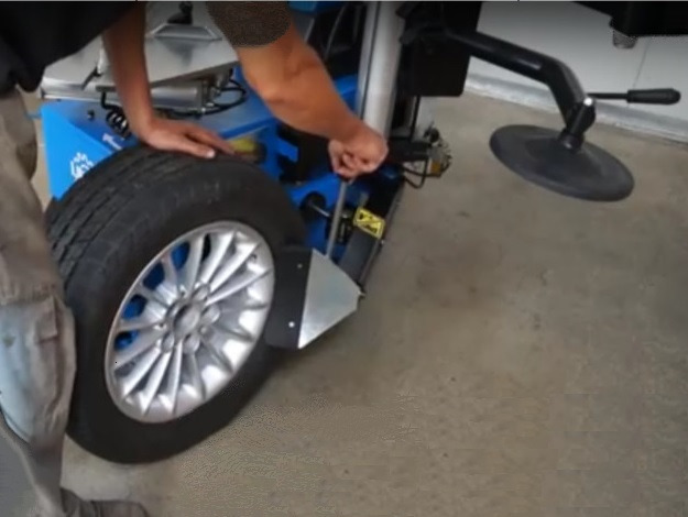 Demontaż opony z felgi przy pomocy montażownicy w warsztacie wulkanizacyjnym.