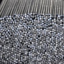 Stos prętów zbrojeniowych o okrągłym przekroju, ułożonych równolegle i ciasno obok siebie. Widoczne końcówki prętów tworzą gęstą mozaikę szarości.