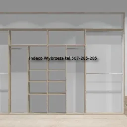 Wnętrze z szafą wnękową z jasnego drewna, trzema czarno-białymi portretami w ramkach i wzorzystą tapetą. Widoczny narożny tapczan.