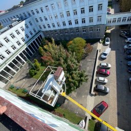 LUX KLIMA - Widok z góry na budynek biurowy z dziedzińcem i parkingiem, z platformą roboczą na wysięgniku, prawdopodobnie podczas prac konserwacyjnych lub montażowych na dachu.