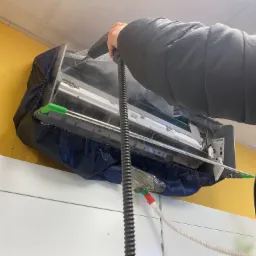 Czyszczenie klimatyzacji parą wodną z użyciem specjalistycznego pokrowca ochronnego, widoczny przewód doprowadzający parę.