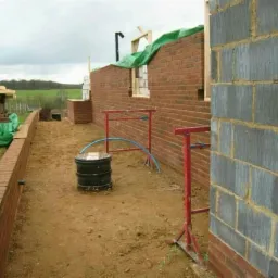 Budowa domu w trakcie: ściany z cegły i bloczków, podpory, elementy konstrukcyjne. Widok na plac budowy w trakcie murowania ścian zewnętrznych budynku.