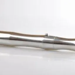 Metalowy, srebrny przedmiot obrobiony na tokarce, leżący na białym tle. Widoczne delikatne refleksy światła i precyzyjne wykończenie detali.