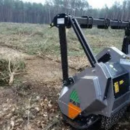 Maszyna do karczowania pni na wycince leśnej, widok z boku. Świeżo wykarczowany teren z pozostałościami gałęzi na tle lasu. Urządzenie z żółtą liną i zielonym logo.