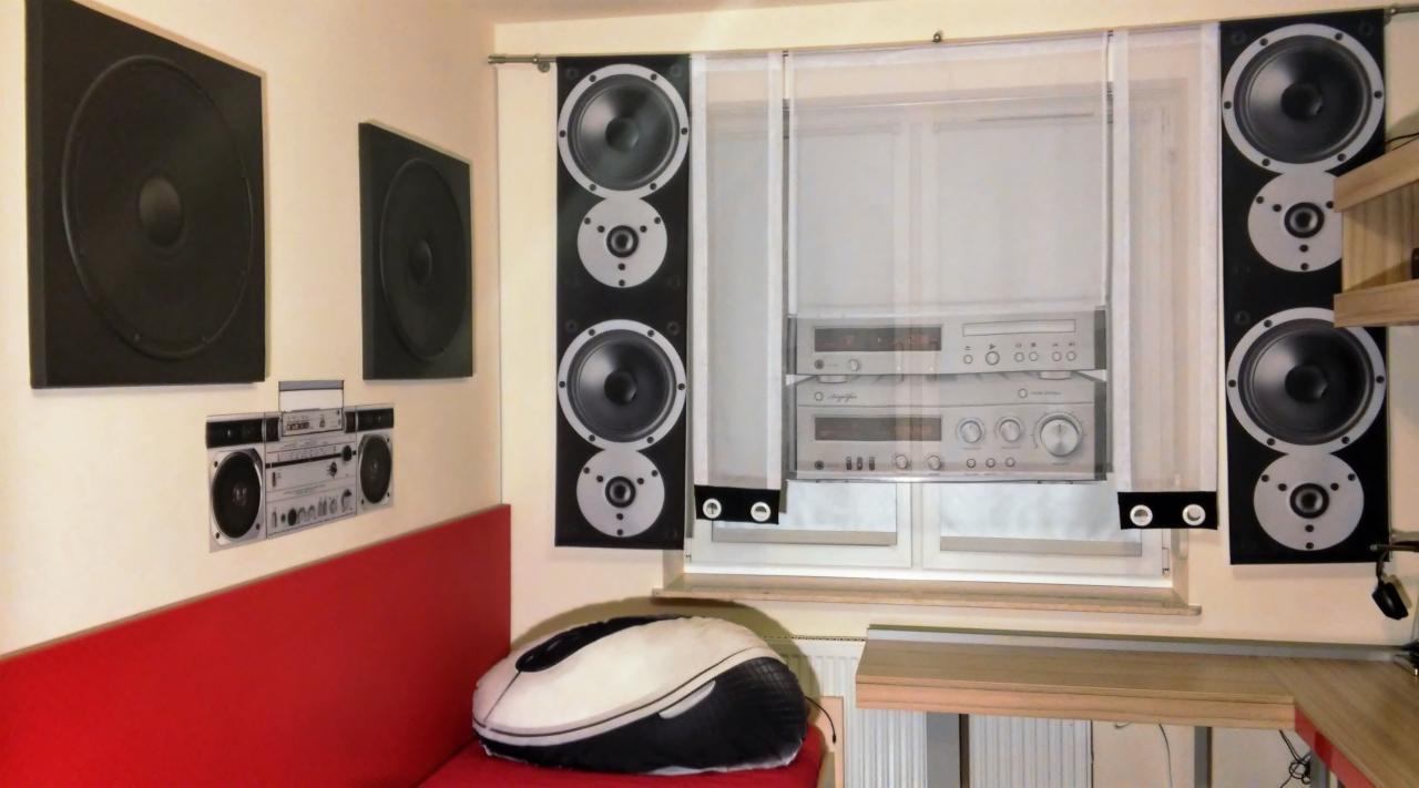 Białe, półprzezroczyste zasłony z nadrukiem sprzętu audio wiszące w oknie. Na ścianie grafiki głośników i boomboxa. Poduszka w kształcie myszy komputerowej.