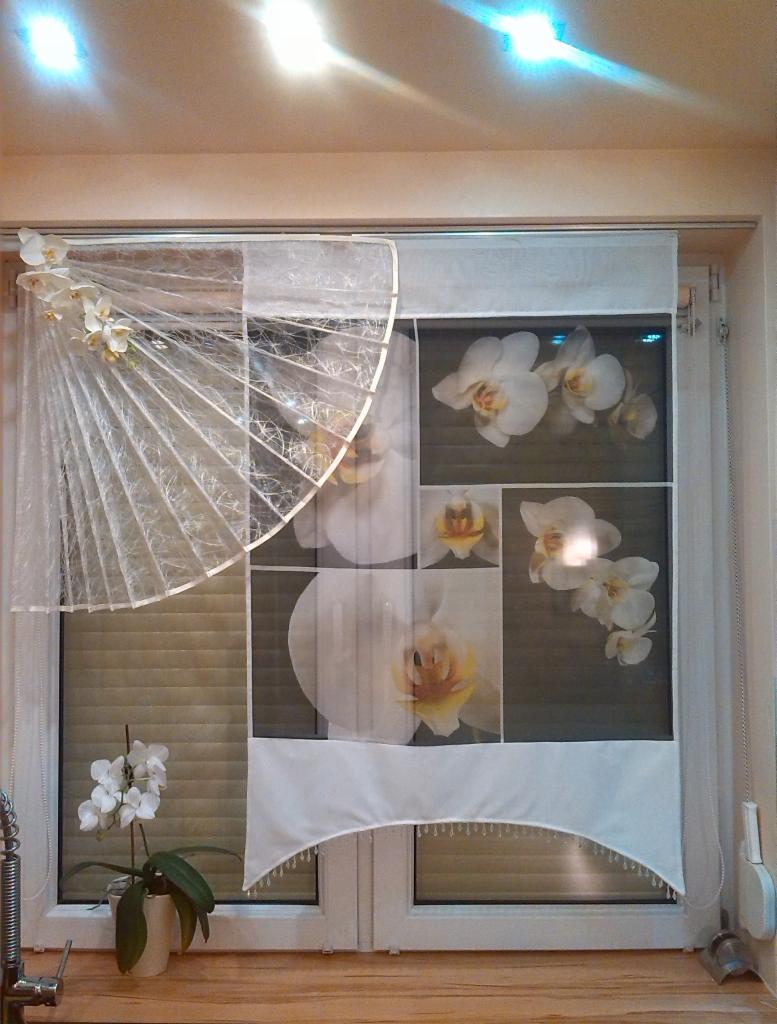 Dekoracja okienna: roleta rzymska z motywem orchidei i wachlarz z kwiatami, dopełniona doniczką z orchideą. Subtelne oświetlenie sufitowe.