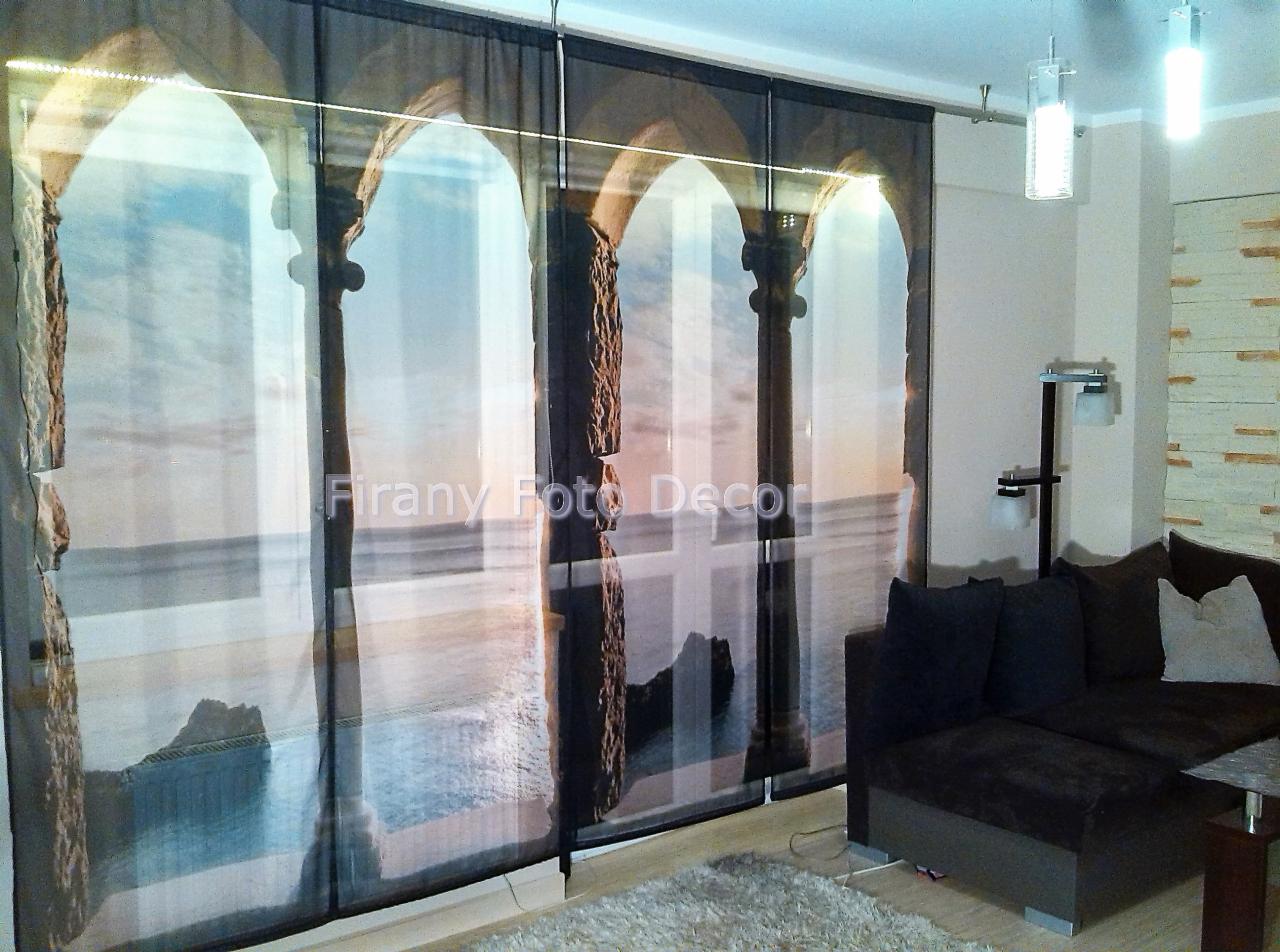 Zasłony panelowe z nadrukiem kolumn i widokiem na morze, w salonie z szarą sofą i dywanem. Nowoczesny design, oświetlenie sufitowe.