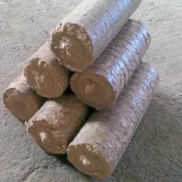 Ułożone brykiety drzewne RUF z widoczną strukturą włókien, gotowe do transportu od producenta z Zaręb Kościelnych. Szary, betonowy plac.