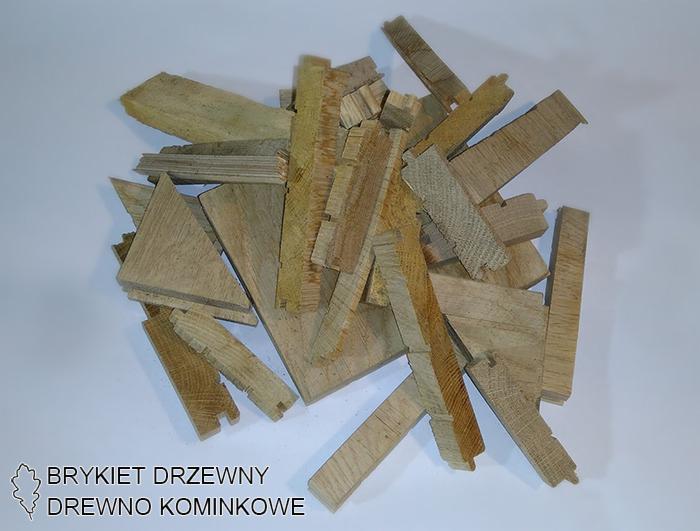 Nieregularne kawałki jasnego drewna ułożone na białym tle, niektóre z widocznymi śladami obróbki, tworzące kompozycję o zróżnicowanych kształtach i fakturach.