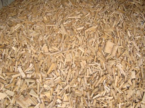 Jasne, nieregularne kawałki drewna, z bliska, tworzące dużą stertę. Widoczne różnice w kształcie i wielkości, niektóre z widocznymi słojami.