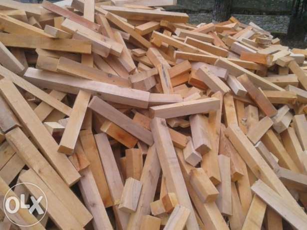 Stos pociętych kawałków jasnego drewna o różnych wymiarach, ułożonych chaotycznie na kupie. Widoczne ślady po cięciu.