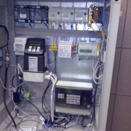E-funia Projekty techniczne, Automatyka przem., Elektryka, kompensacja mocy biernej, Falownikowe Układy Napędowe - Otwarta szafa sterownicza z widocznymi modułami, przewodami i urządzeniami marki Siemens. Widoczne elementy automatyki przemysłowej i okablowanie wewnątrz obudowy.