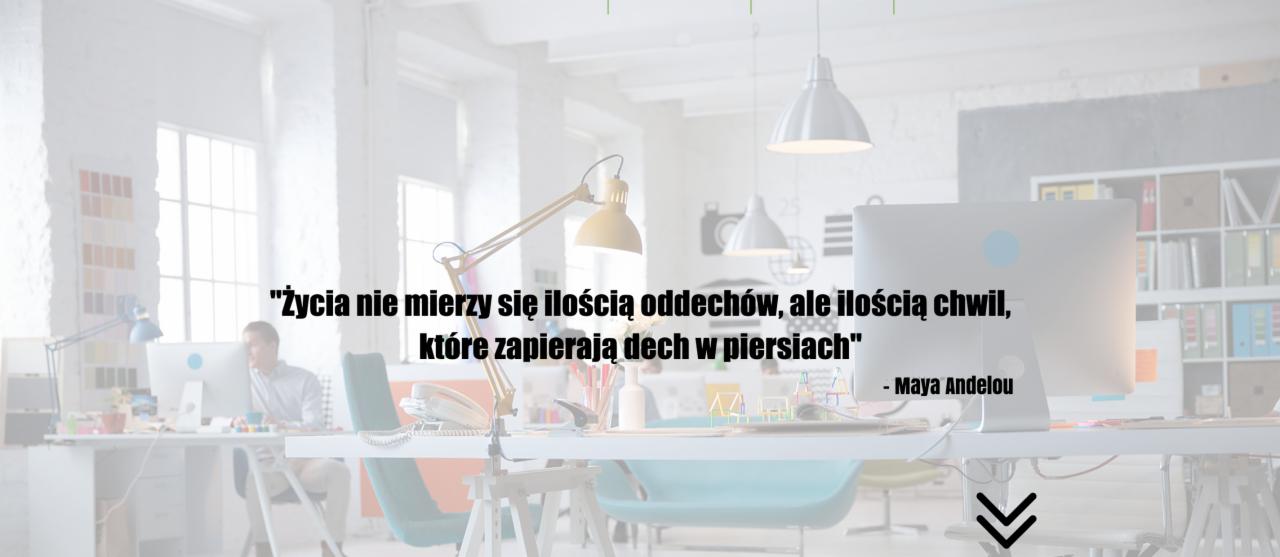 Jasne biuro z cytatem Maya Angelou na monitorze. Minimalistyczny design, lampa na biurku, komputer iMac. W tle pracownik przy innym biurku.