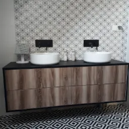 Nowoczesna łazienka z wiszącą szafką pod umywalki nablatowe, czarną armaturą i wzorzystą tapetą oraz podłogą w geometryczny deseń.