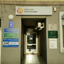 Wejście do budynku z szyldem Nationale Nederlanden, obok tabliczki informacyjne biur: podatkowo-księgowego, stomatologicznego i neurologicznego.