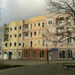 Kolorowy budynek biurowy z balkonami i szyldem 'MEDICAL Beta' w jesiennej scenerii.