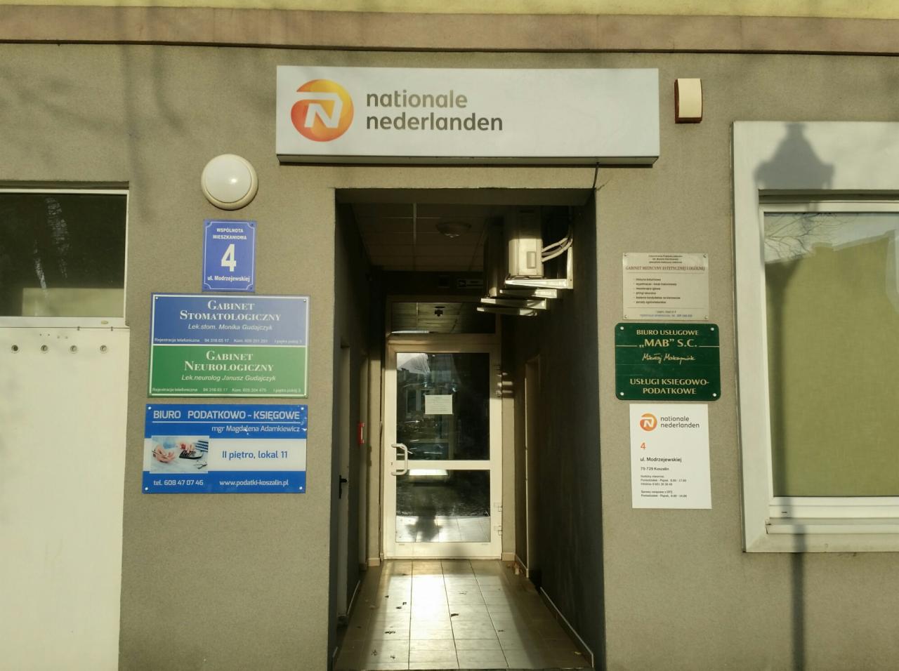 Wejście do budynku z szyldem Nationale Nederlanden, obok tabliczki informacyjne biur: podatkowo-księgowego, stomatologicznego i neurologicznego.