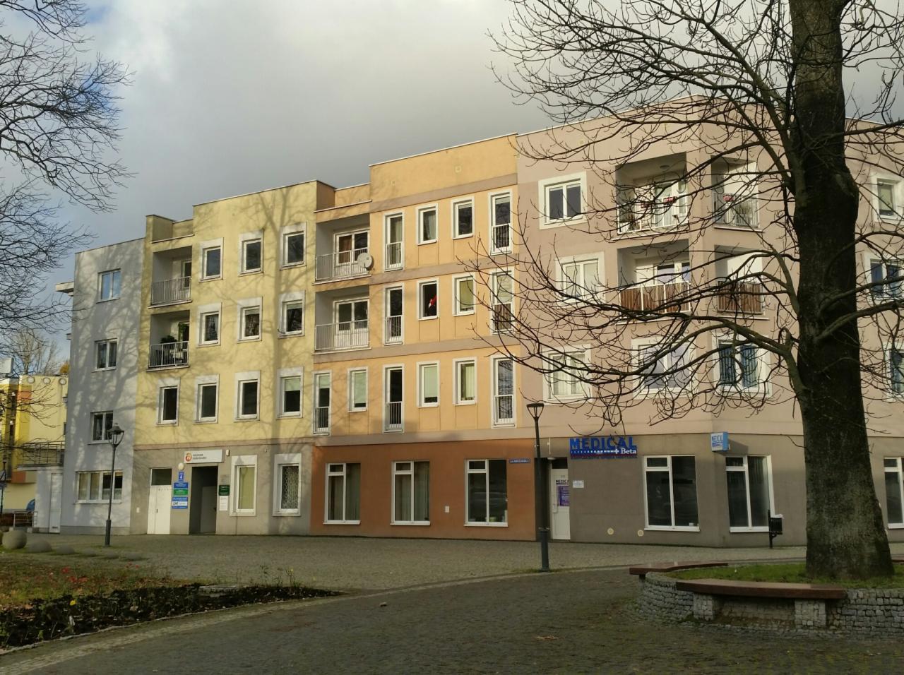 Kolorowy budynek biurowy z balkonami i szyldem 'MEDICAL Beta' w jesiennej scenerii.