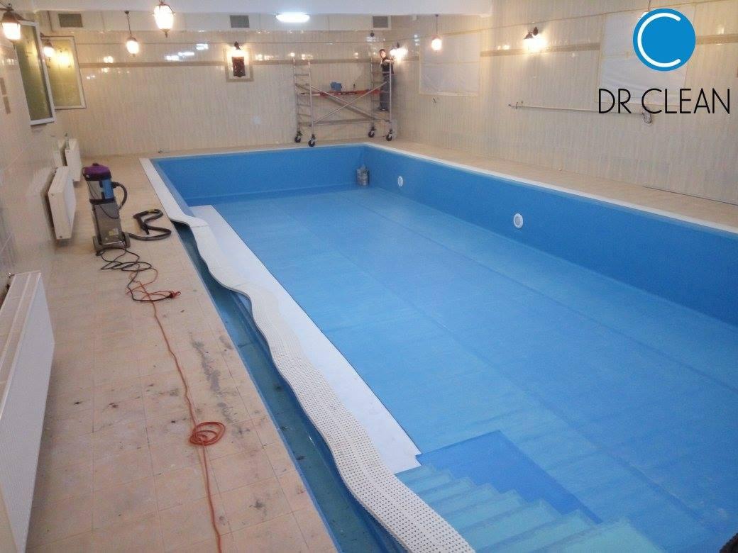 Wnętrze basenu po czyszczeniu, z niebieską wodą i odkurzaczem obok. Logo firmy sprzątającej w prawym górnym rogu, drabina serwisowa w tle.