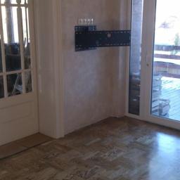 FHU Jarko - Ułożony parkiet w jodełkę francuską w jasnym odcieniu, widoczny uchwyt do telewizora na ścianie, Pilawa. Wykończenie podłóg z naturalnego drewna.