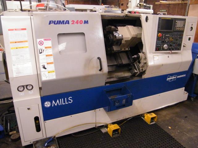 Tokarka CNC Puma 240M z otwartą komorą roboczą, widoczny panel sterowania i narzędzia. Detal: logo Mills na niebieskim pasie.