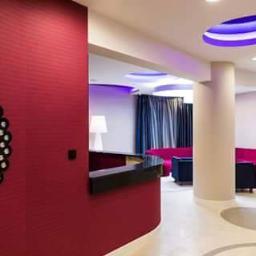 PUH Konkurent Bartłomiej Pawelec - Nowoczesne wnętrze z czerwonymi ścianami, dekoracyjnym lustrem i elementami oświetlenia sufitowego w kolorze fioletowym. Widoczna recepcja i strefa wypoczynkowa.