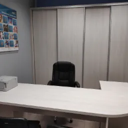 Biuro ubezpieczeniowe: biurko w kształcie litery L z czarnym krzesłem obrotowym i drukarką, na ścianie plakat informacyjny Wiener Insurance Group.