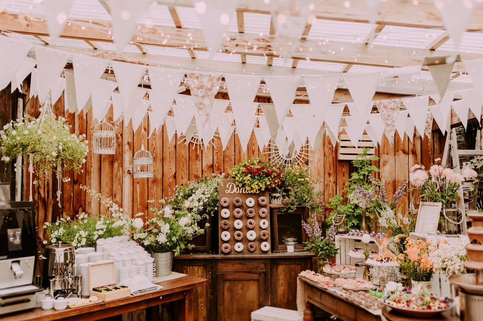 Dekoracyjny stół z pączkami, fontanną czekoladową i kwiatami na drewnianym tle z girlandami, idealny na przyjęcie.